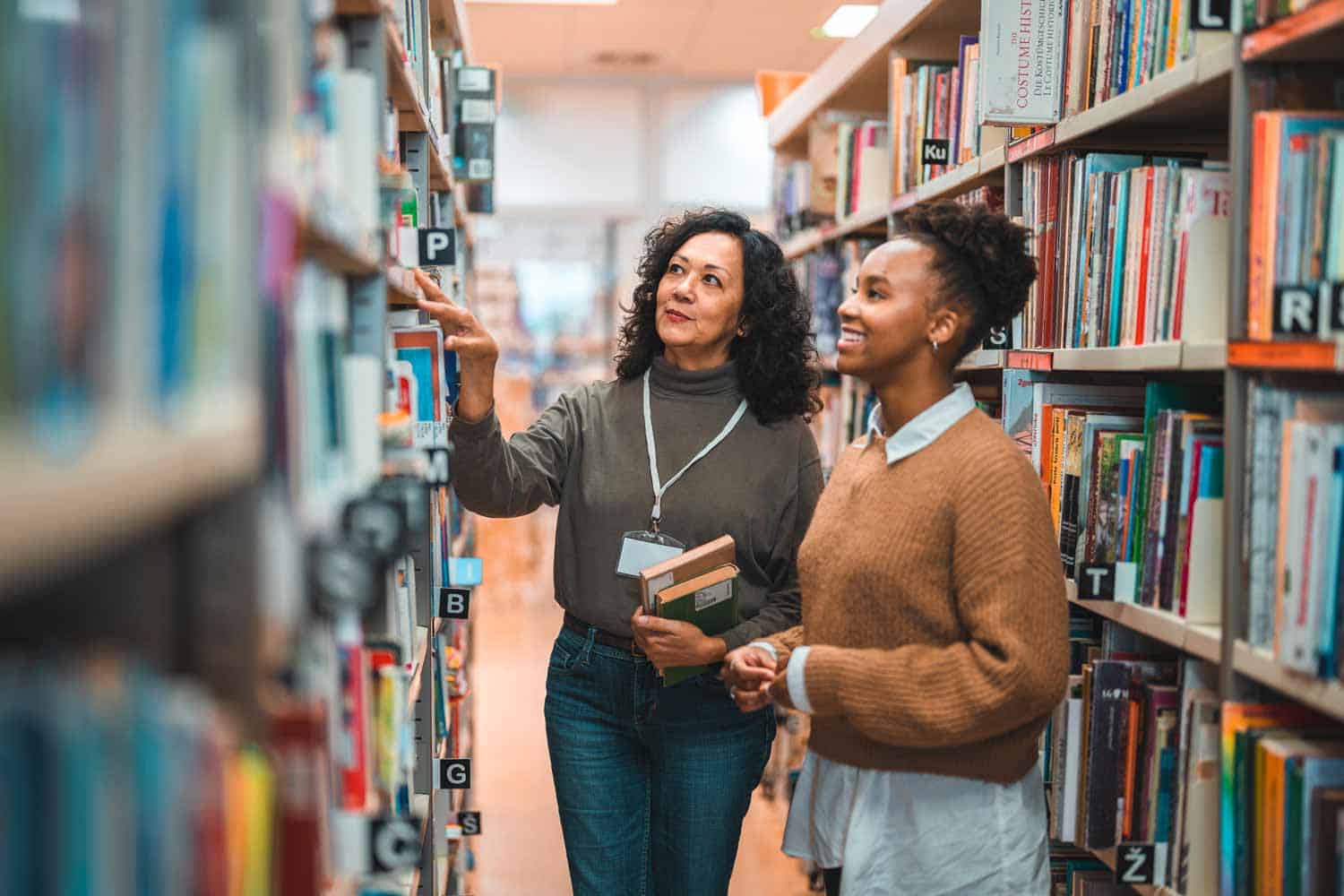 Bibliothekarin zeigt einer Bibliotheksbesucherin ein Buch