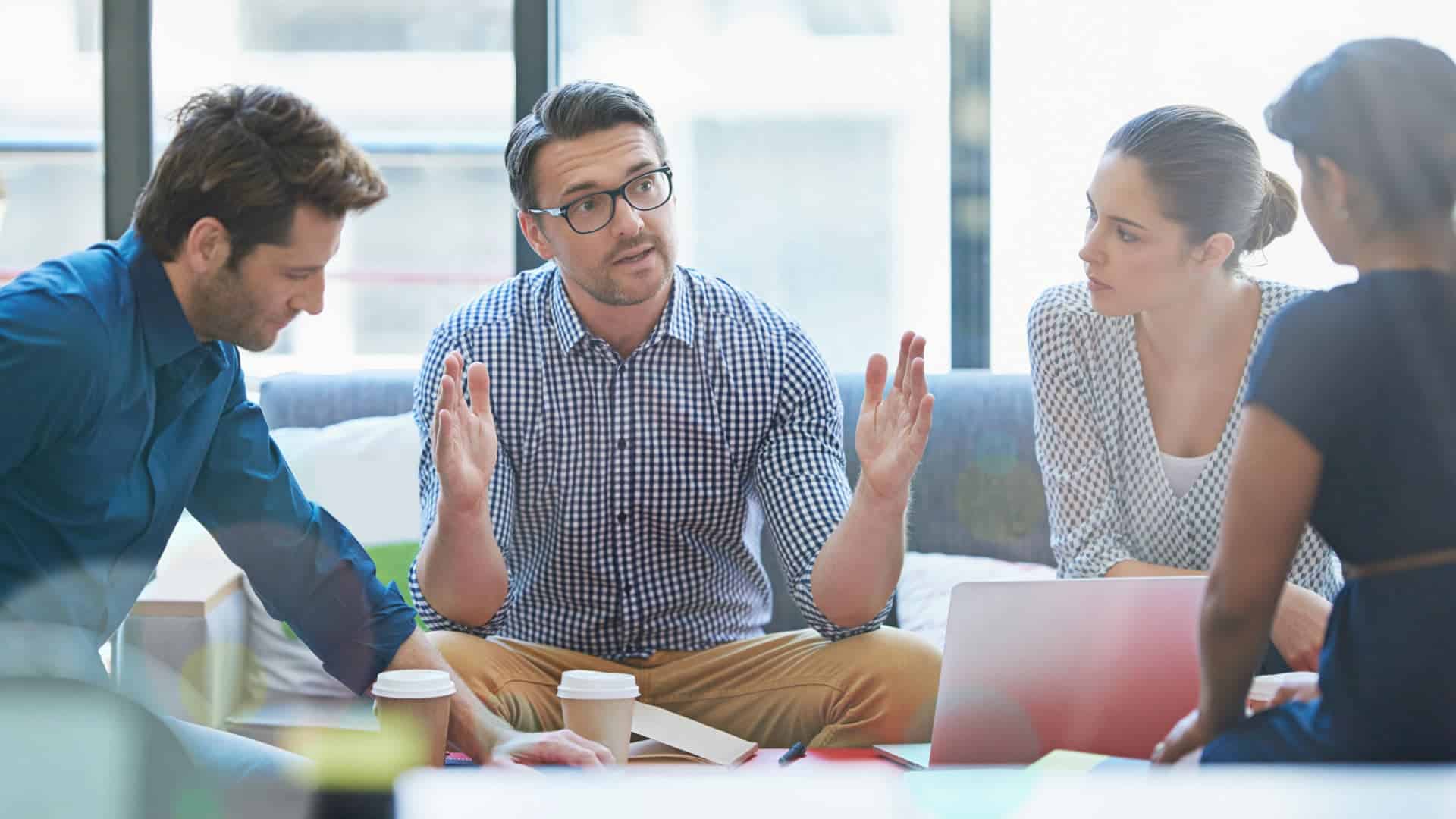 Vier Personen in Diskussion bei Meisterplan-Meeting.