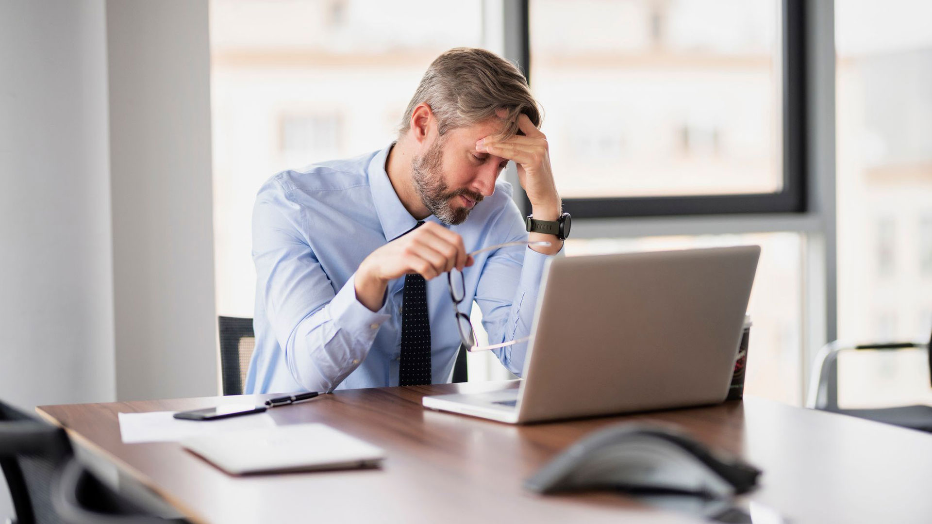 A man sitting at a laptop and looking stressed.